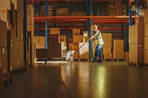 warehouse worker pushing a hand pallet truck between rows