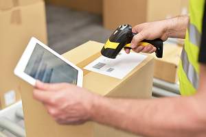 warehouse worker scanning boxes as they run through a conveyor belt