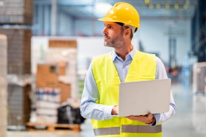 warehouse manager walking through inventory with his laptop