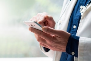 doctor using their phone to access patient portals and connect with patients