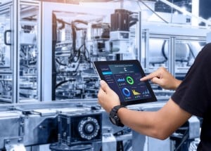 factory worker looking at the state of their machinery with equipment condition monitoring applications on a tablet