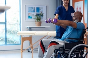 medical professional helping a man in a wheelchair with rehabilitation