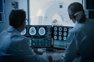 doctor and radiologist discuss diagnosis while watching procedure and monitors showing brain scans results from medical imaging software