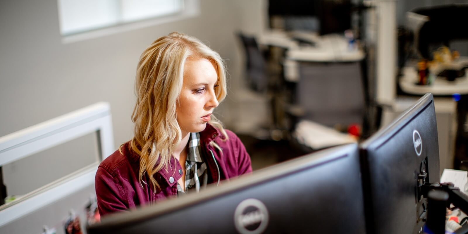 women working on dual-screen computer system