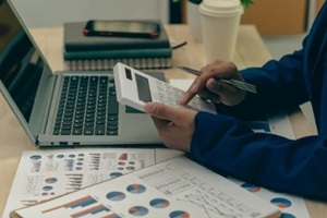 young asian male businessman is pressing a calculator to calculate income