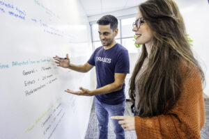 2 team members working on a white board. 