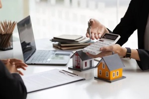 real estate agent holding a calculator, presenting a price quote to a client for a house