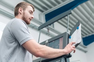 worker in the metal industry entering data on screen of a modern machine tool in factory